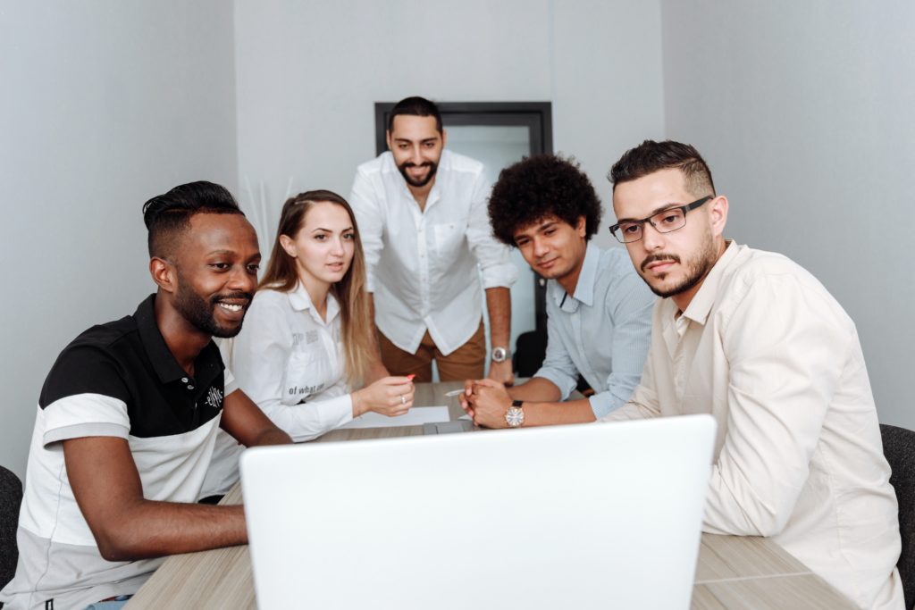 A group of workers huddled around a laptop.